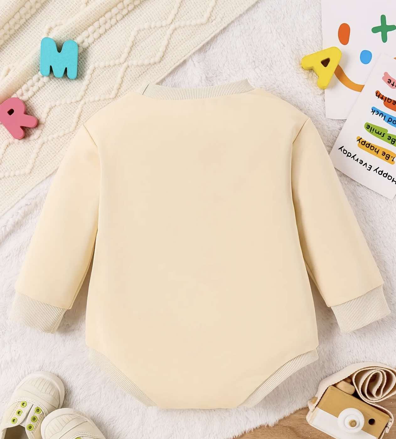 Baby wearing a "Cousin Crew" long-sleeve romper, smiling and cozy in soft cotton fabric.