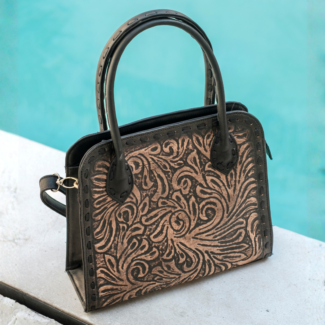 Blackwood Shoulder Bag from House of Hide in dark brown leather with hand-tooled detailing and matching dark brown handle being displayed against turquoise background
