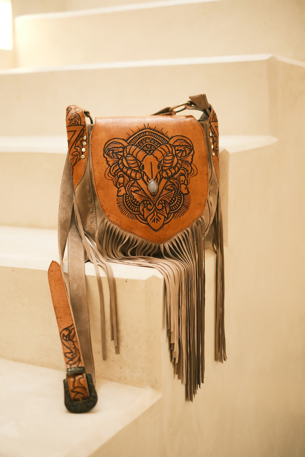 Boho cowgirl crossbody bag featuring detailed bullhorn tooling, natural stone centrepiece, and flowing fringe by House of Hide.