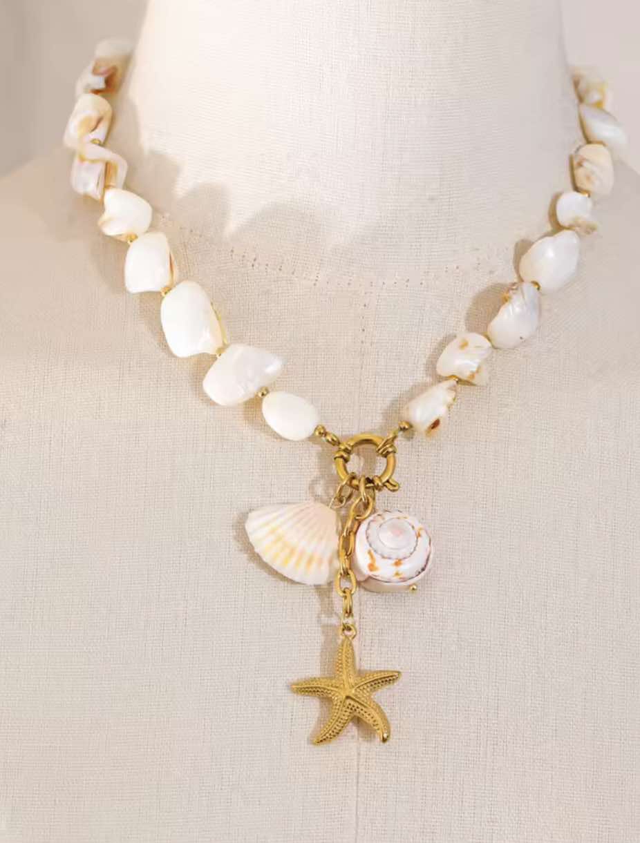 Close-up of gold scallop and spiral charms on waterproof baroque shell necklace