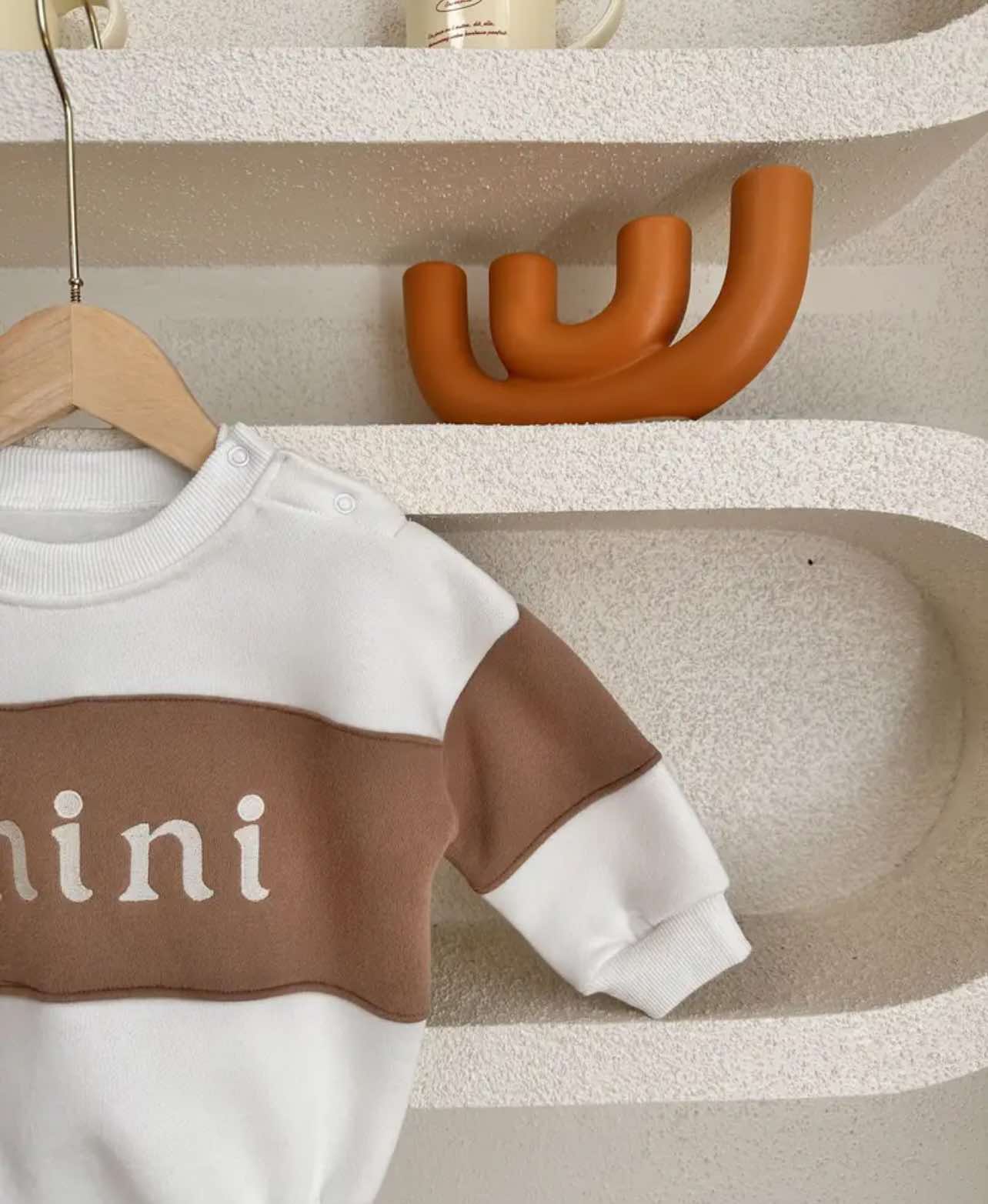 Close-up of the embroidered ‘Mini’ logo on a gender-neutral baby romper, a stylish choice for kids' clothing.