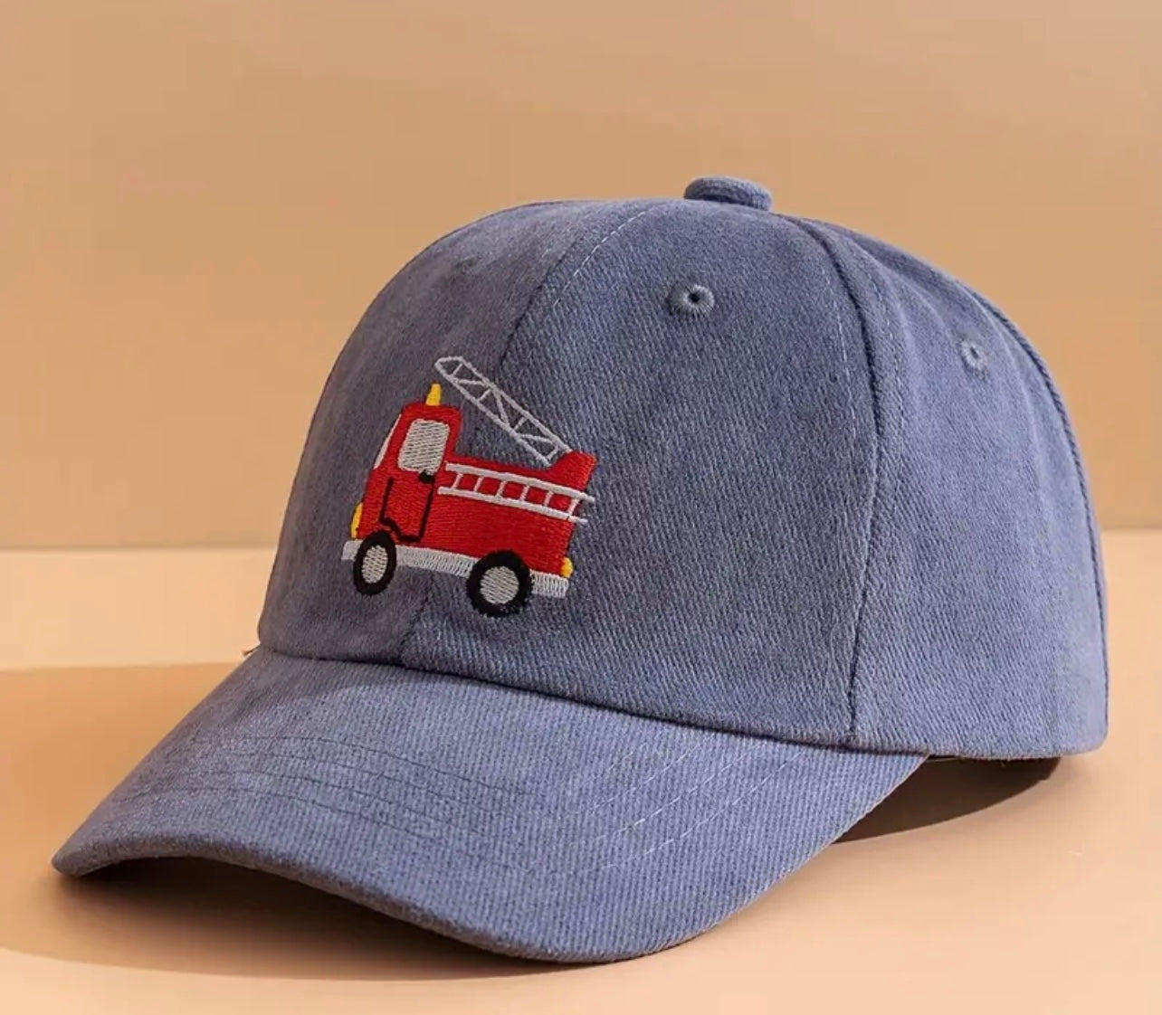 Close-up of the playful firetruck design on the hat, highlighting the vibrant colors and intricate stitching