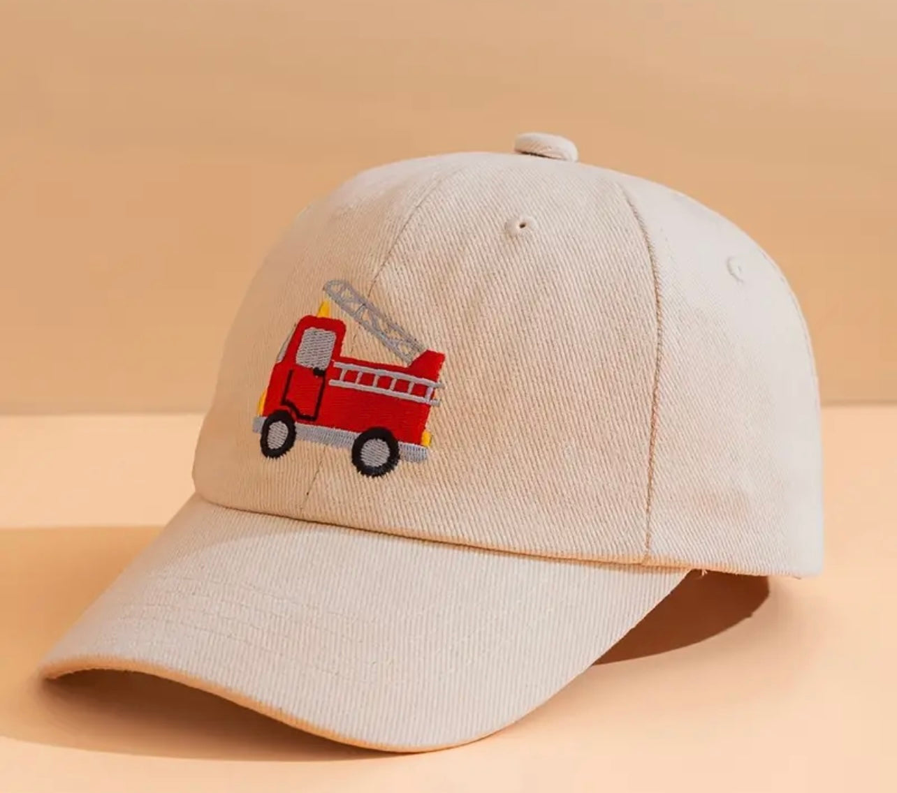 Cream kids' firetruck hat, displaying its soft fabric and sturdy construction, perfect for all-day wear