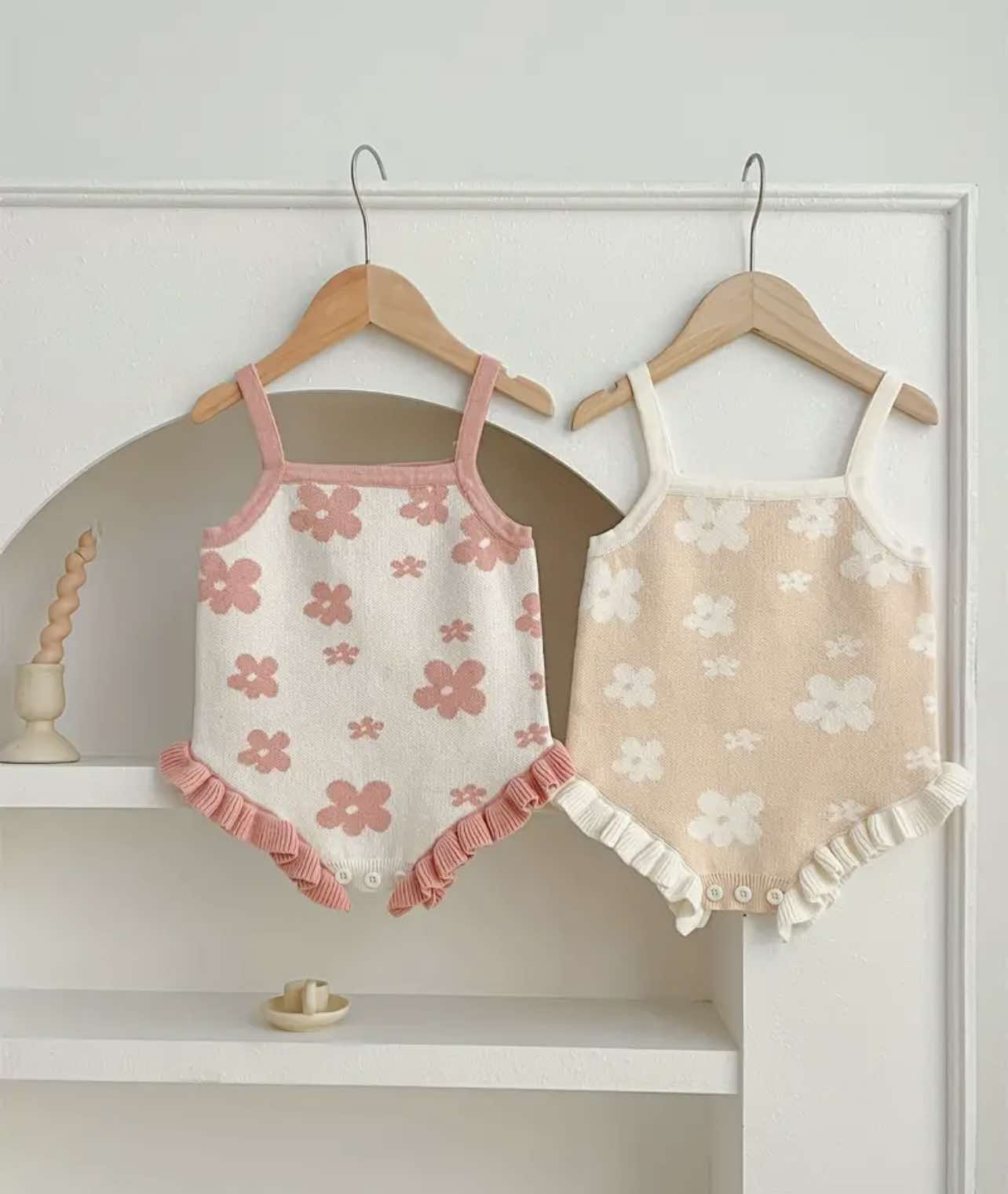 Floral Knitted Romper in soft pink, laid flat to showcase its delicate floral pattern and shoulder strap design