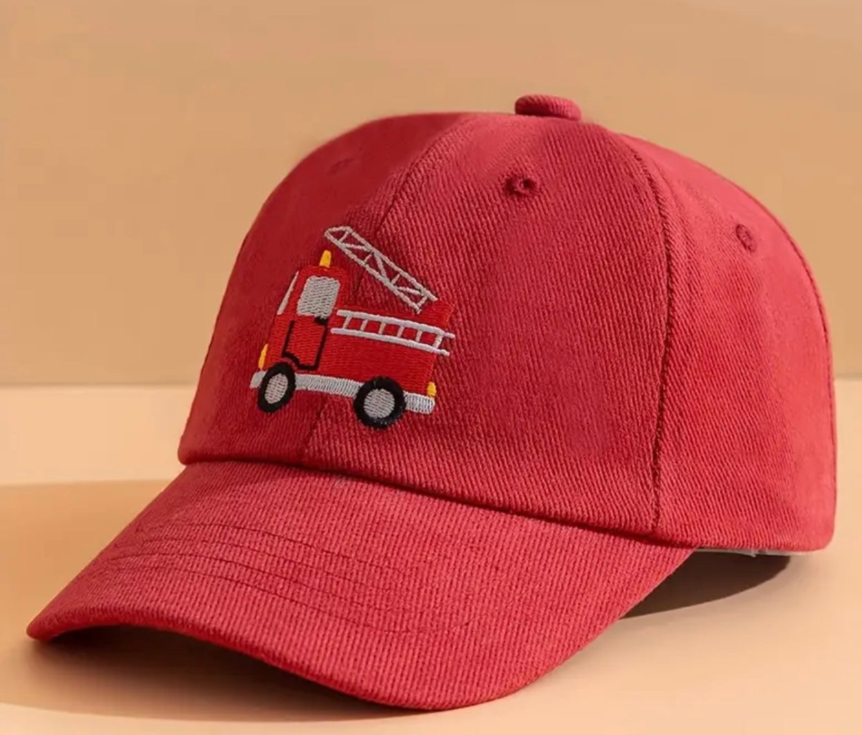 Front view of the vibrant kids' firetruck hat, complete with a bold fire engine design and a bright red brim