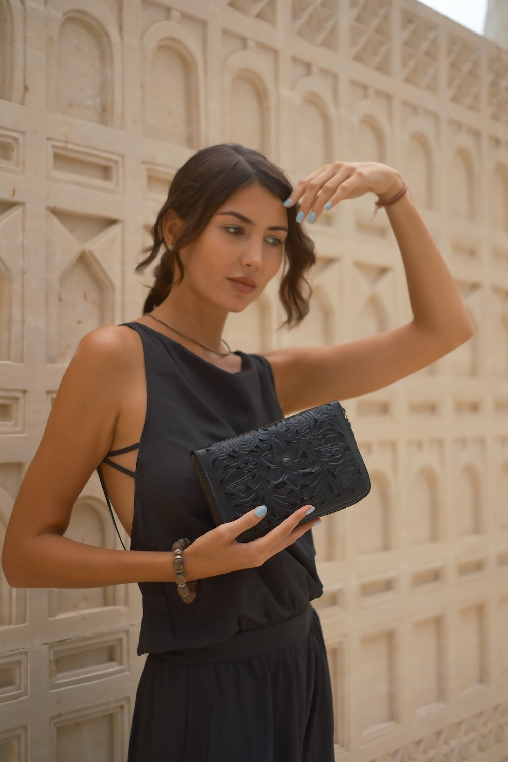 Hand‑carved black leather clutch wallet with stone detail, 20 card slots, and secure zip fastening.