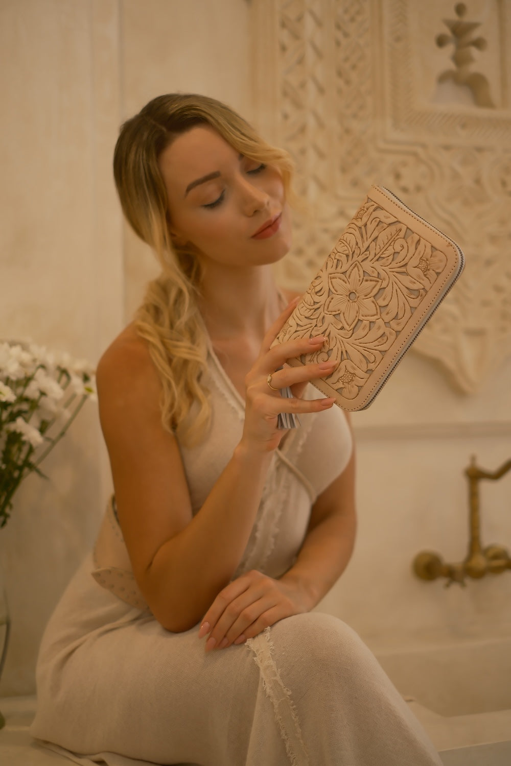 Hand‑carved cream leather clutch wallet with stone detail, 20 card slots, and secure zip fastening.