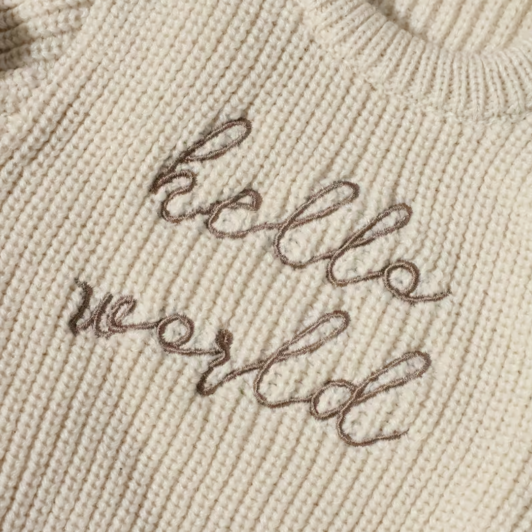 Little Wrangler Knit Romper Set from House of Hide in cream beige ribbed knit with brown cursive hello world embroidery across chest being displayed in close-up