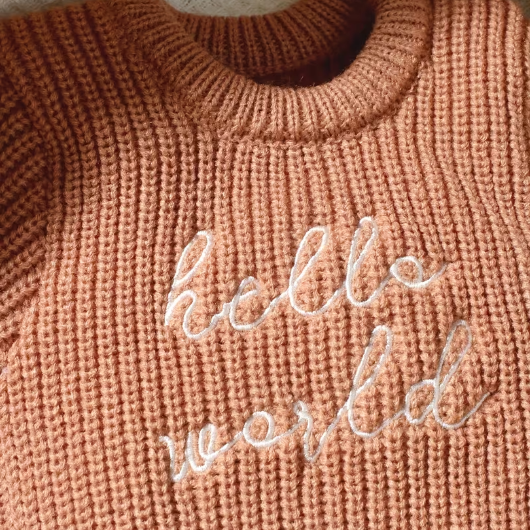 Little Wrangler Knit Romper Set from House of Hide in terracotta ribbed knit with white cursive hello world embroidery across chest being displayed in close-up