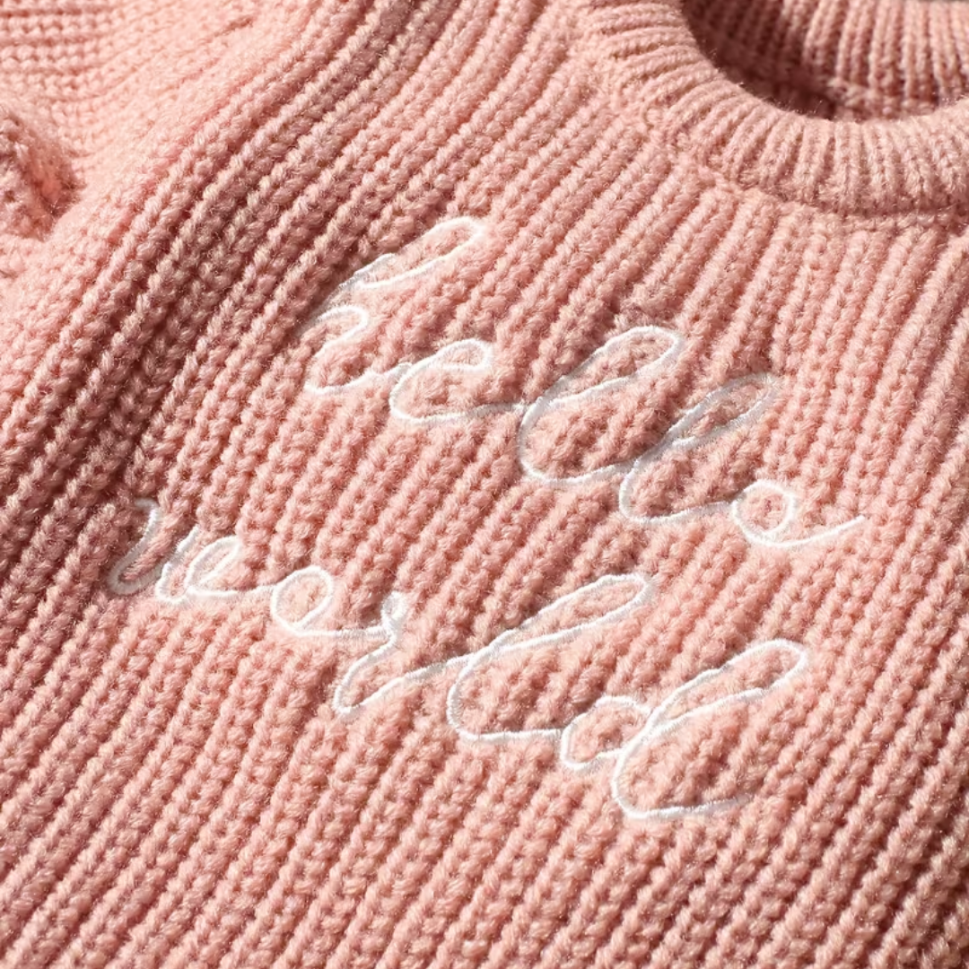 Little Wrangler Knit Romper Set from House of Hide in pink ribbed knit with white cursive hello world embroidery across chest being displayed in close-up