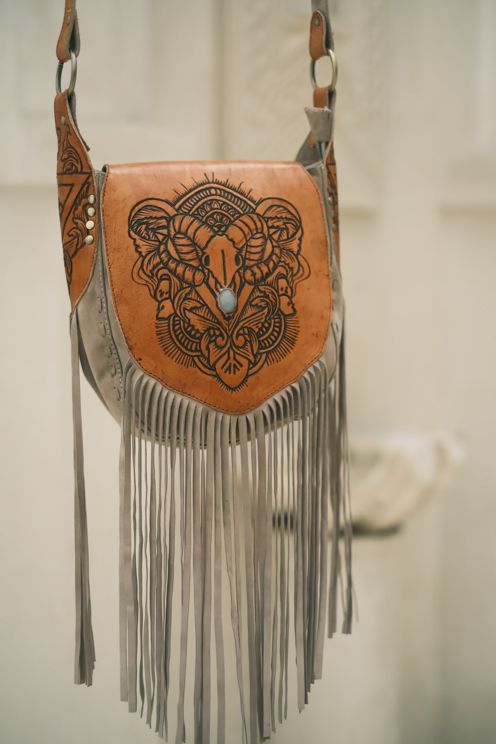 Sierra Western Fringe Bag by House of Hide—handcrafted leather . House of Hide Sierra Western Fringe Bag in tan leather with hand-tooled bullhorn design, stone accent, and long grey suede fringe.