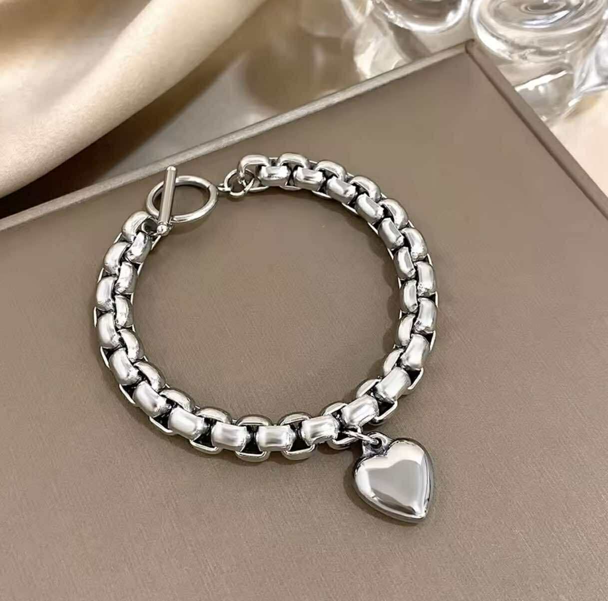 Silver stainless steel heart charm bracelet with open cuff design and polished finish