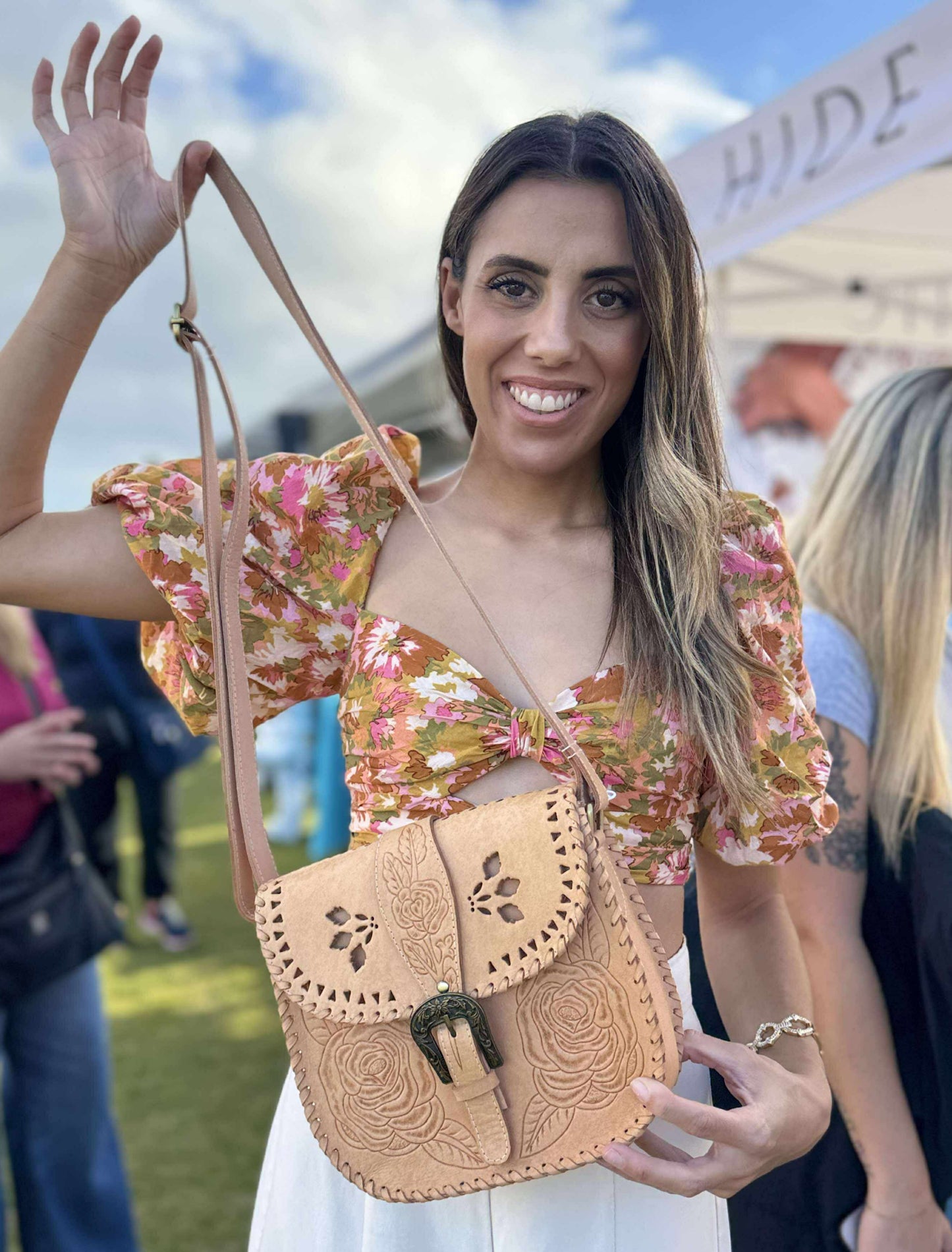 Woman holding a small Western-style tan leather handbag with buckle detail boho country fashion