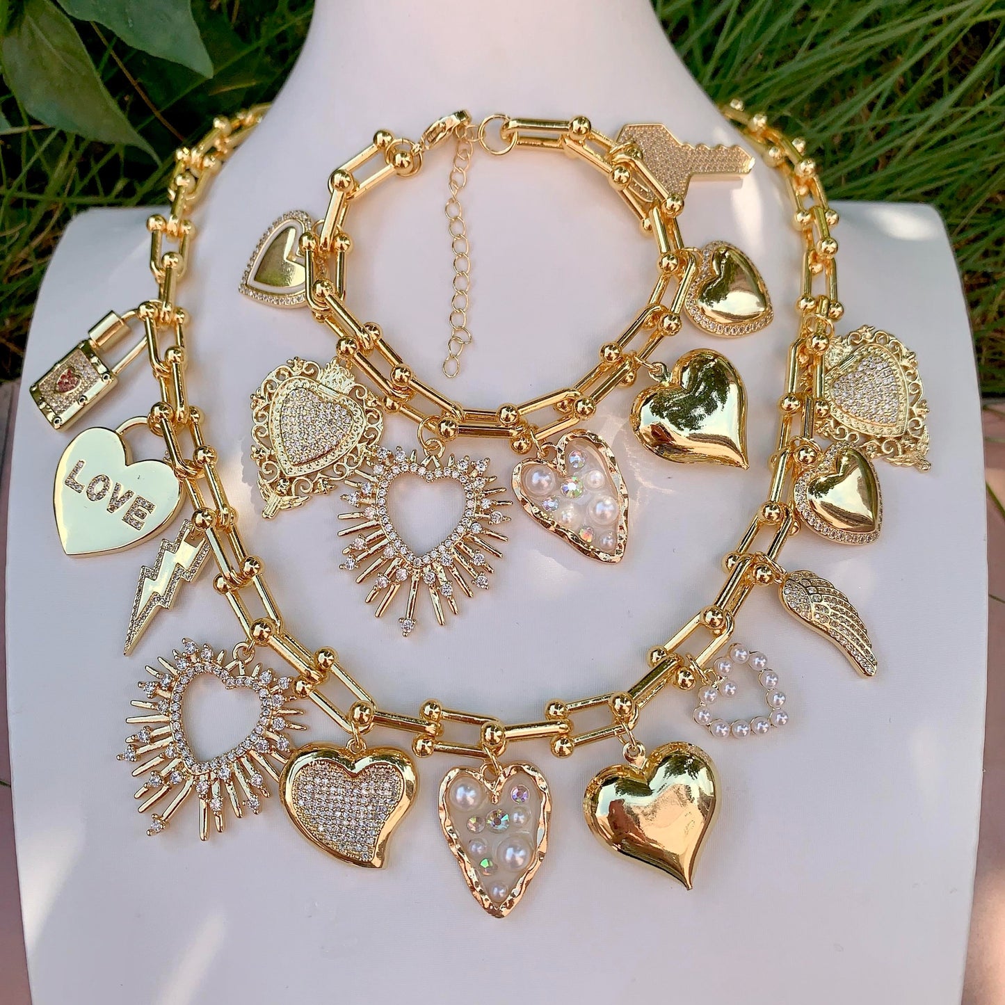 Gold charm chain with various heart-shaped charms on a white surface.
