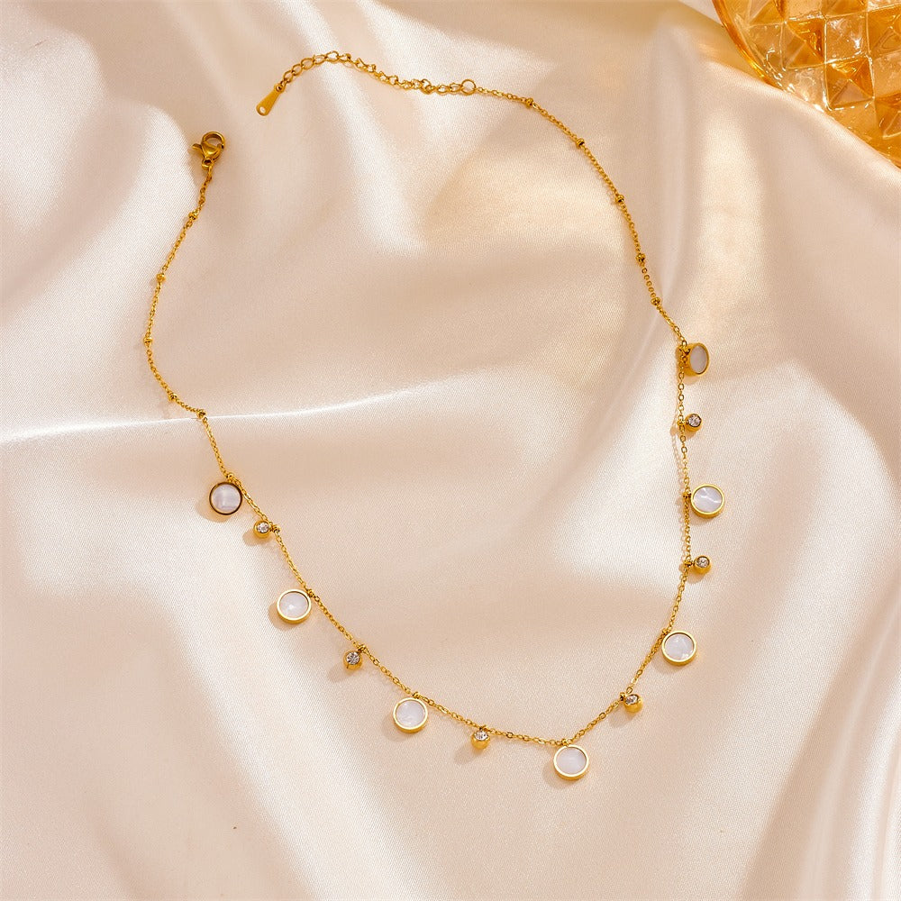 Gold necklace with small round pendants on a soft beige fabric background