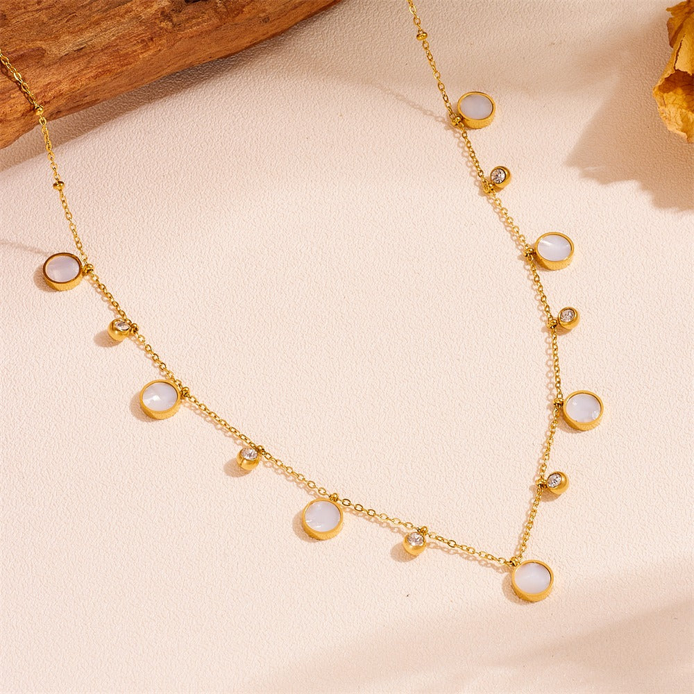 Gold necklace with white stones on a beige background