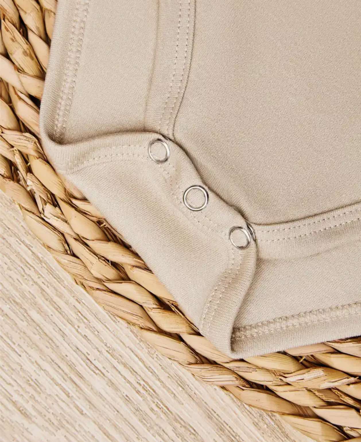 Close-up of breathable, stretchy cotton fabric on the "Future Gate Opener" baby onesie.