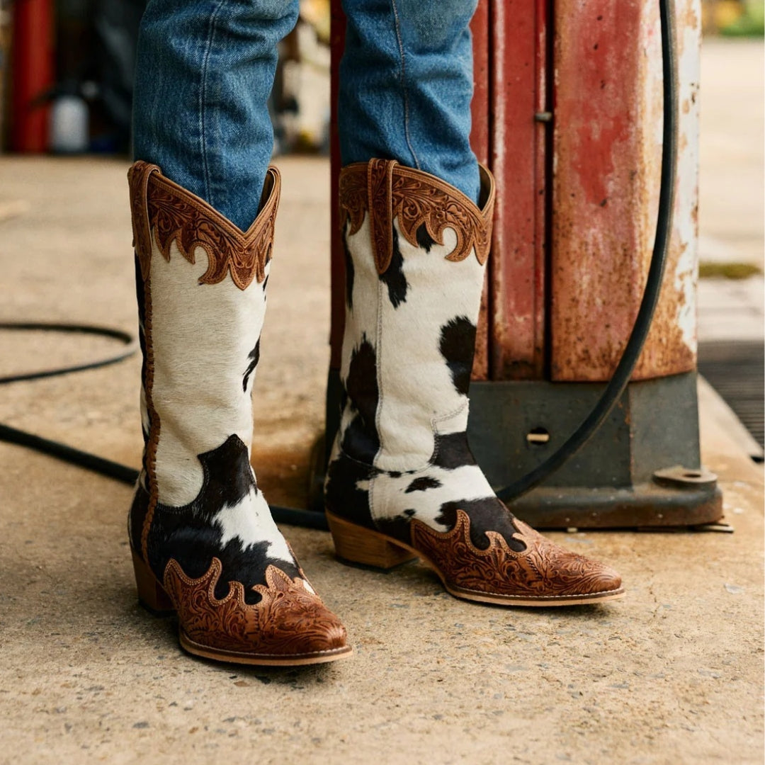 Adelaide cowboy boots worn with blue jeans, showing black and white cowhide and honey-toned tooled leather.