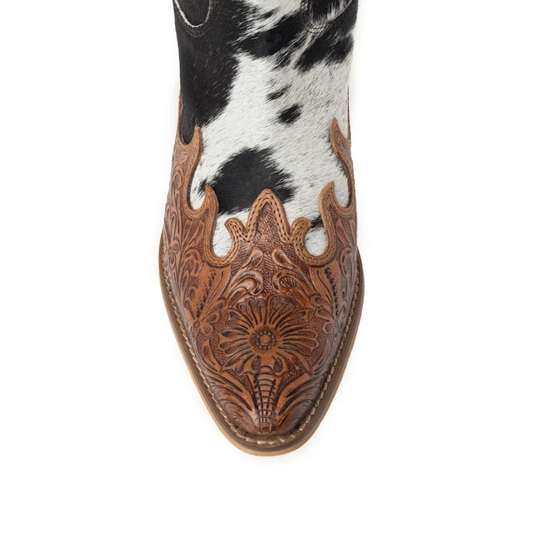 Close-up of the Adelaide boot’s snip toe with honey-toned floral-tooled leather over black and white cowhide.