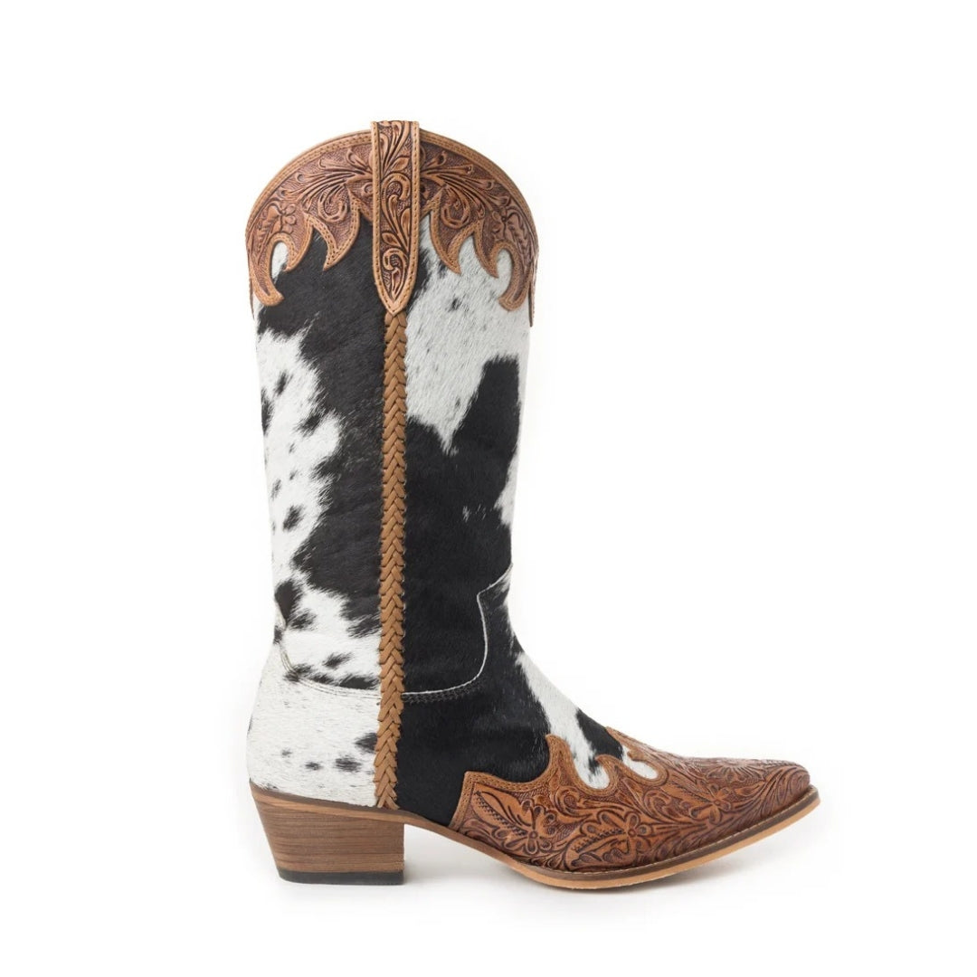 A single western cowboy boot with a black and white cowhide pattern shaft, brown tooled leather details, and a low stacked heel, shown against a plain white background.