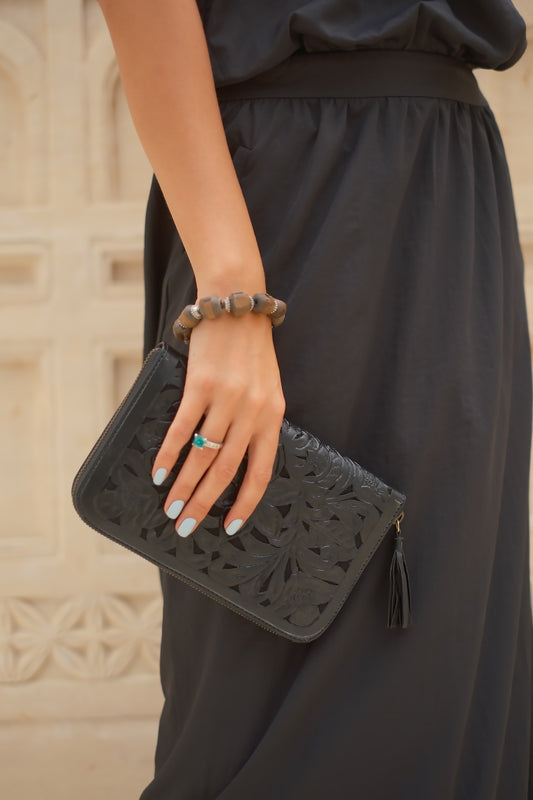 Artisan black leather wallet with hand‑tooled floral design, zip closure, and detachable tassel, ethically made in Australia.