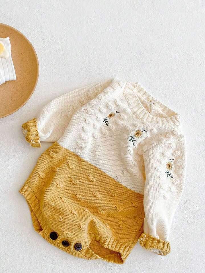 Baby romper with hand-knit sunflower details and textured accents.
