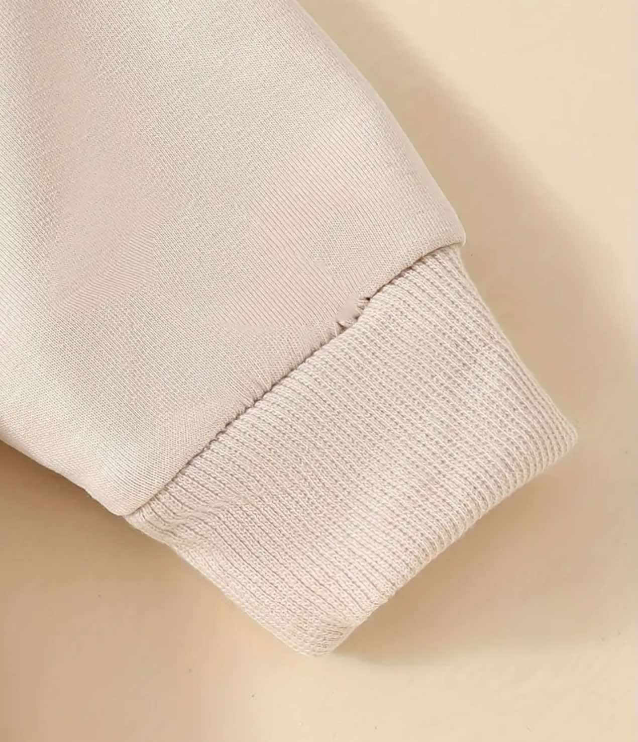 Back view of the beige long-sleeve onesie showcasing its simple, elegant design.