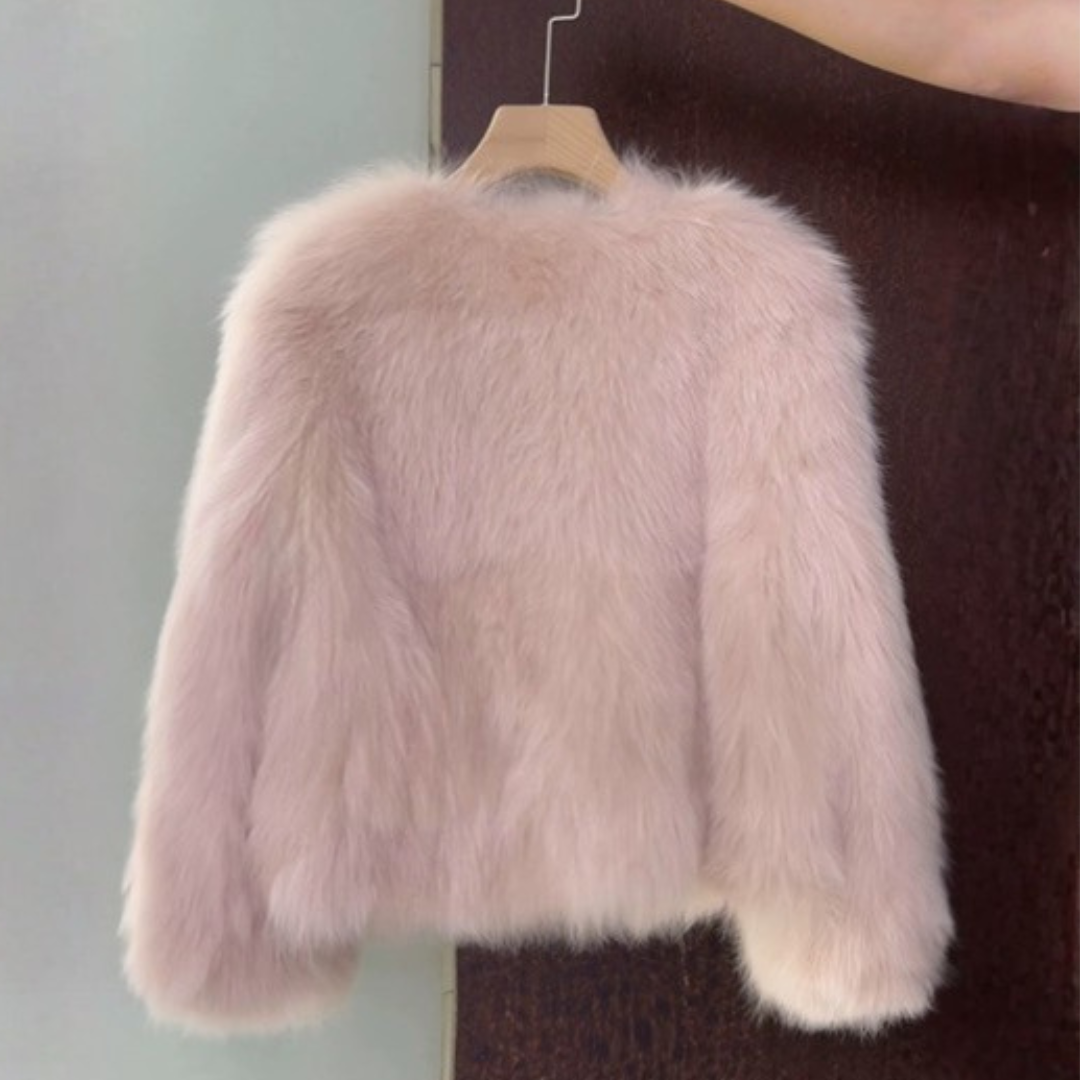 Cropped Faux Fur Jacket from House of Hide in plush blush pink featuring vegan leather placket and pocket trim, gold engraved button hardware, dramatic voluminous sleeves, cropped silhouette being displayed as playful yet polished layering piece on styled backdrop