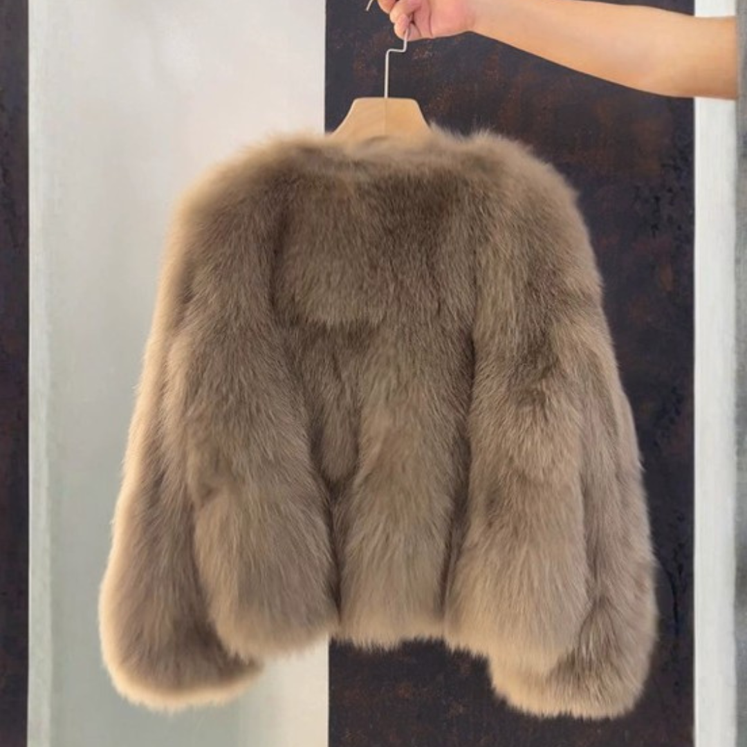 A woman wears Bailey Jacket from House of Hide in plush camel faux fur with vegan leather placket details, engraved gold button closures, dramatic full sleeves, cropped boxy fit being styled over casual denim in editorial fashion shot