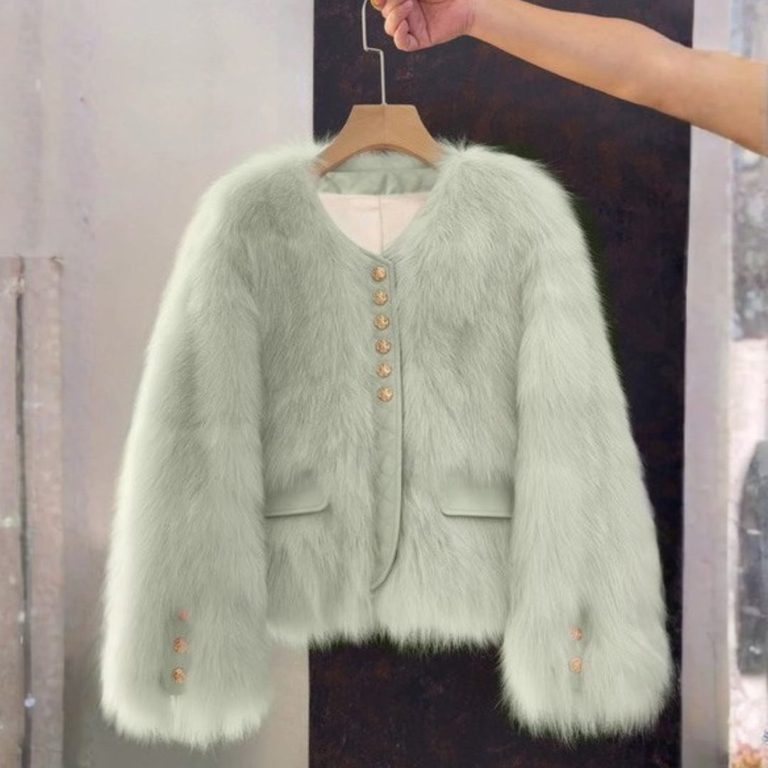 Bailey Jacket from House of Hide in cool muted sage green faux fur with smooth vegan leather trim, engraved gold buttons, fitted cropped length with full sleeves, quiet standout jacket designed to pair easily with neutrals or darker layers