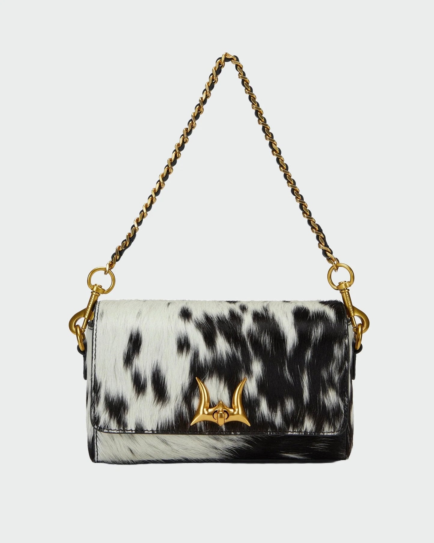 House of Hide genuine leather black and white cow print handbag with a gold-tone chain strap showcased on a light gray studio background