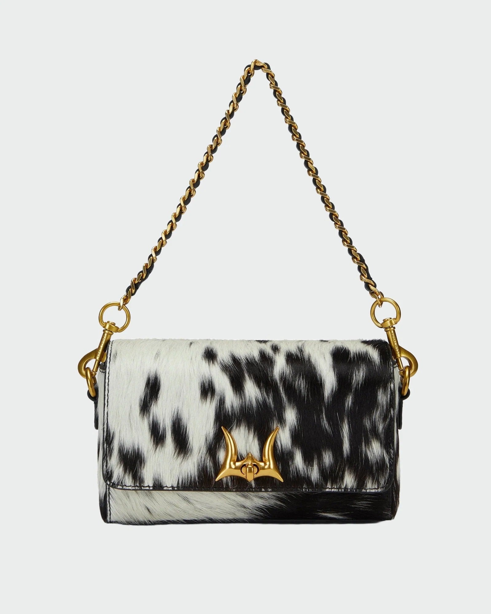 House of Hide genuine leather black and white cow print handbag with a gold-tone chain strap showcased on a light gray studio background