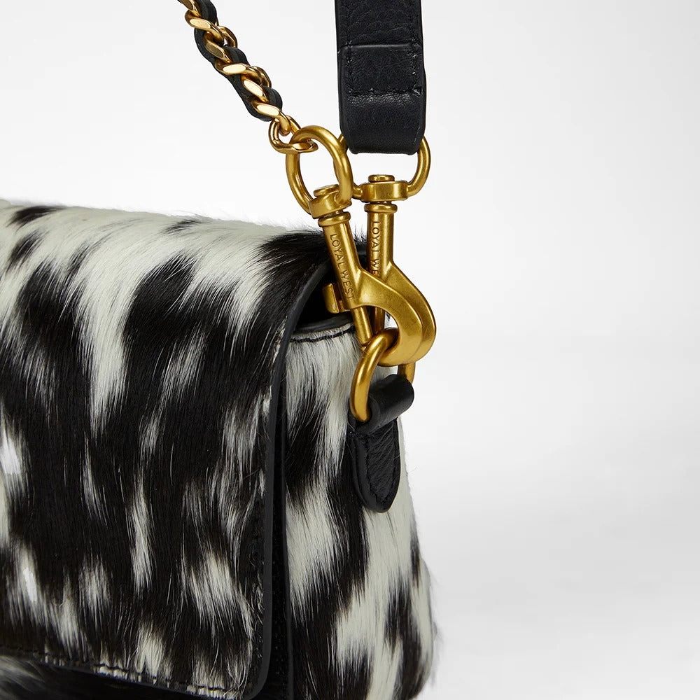 House of Hide genuine leather black and white patterned handbag featuring a gold clasp detail on a light gray studio background