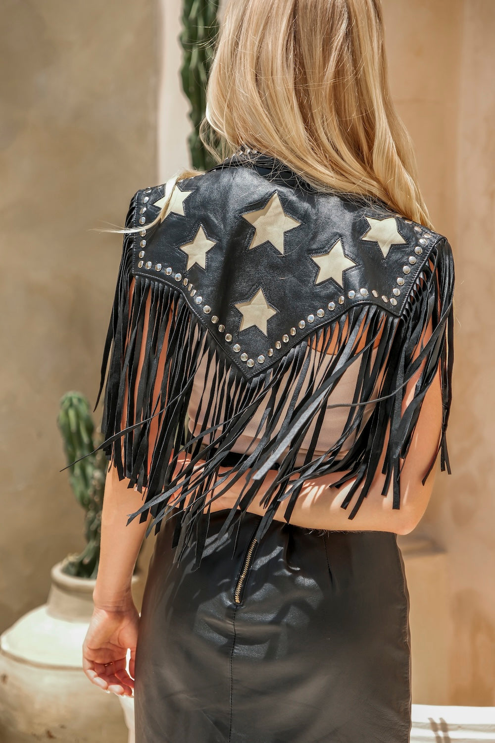 Bold black leather bolero with white star and fringe. Handmade Western jacket with studs, cropped cut, and boho-country attitude.