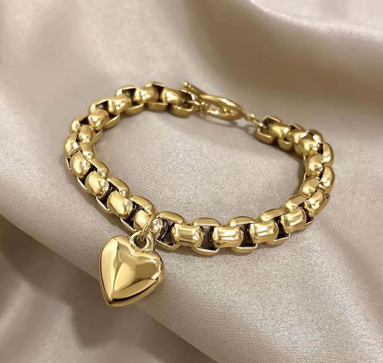 Close-up of Heartline Bracelet in gold showing puffed heart charm and smooth metal finish