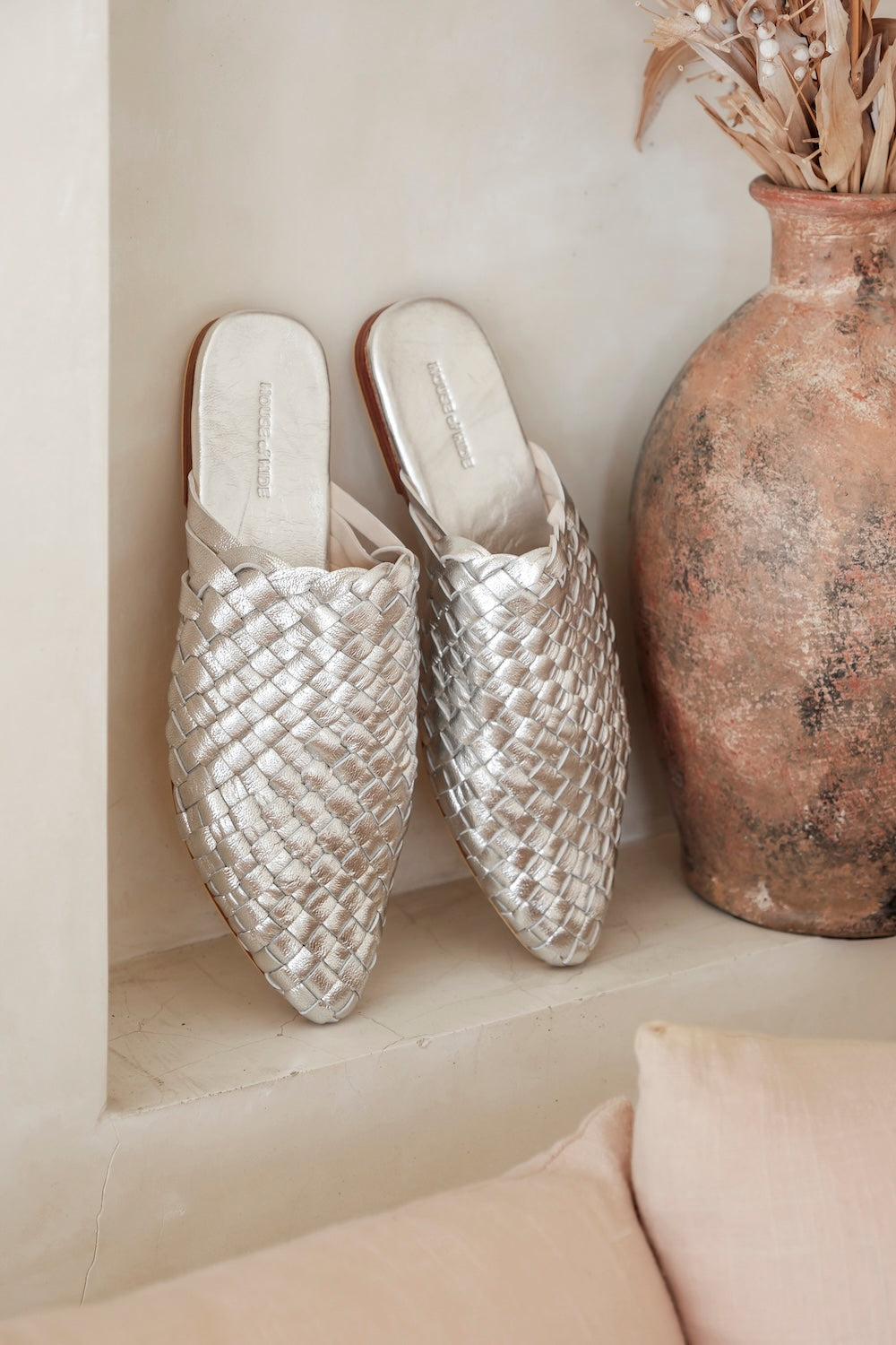 Close-up of braided backless slip-on sandal with a softly pointed toe and slim silhouette, crafted from genuine silver-toned leather