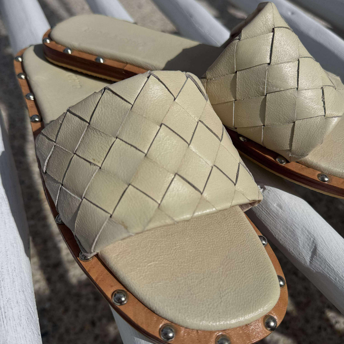 Pair of beige woven sandals with brown straps on a white surface