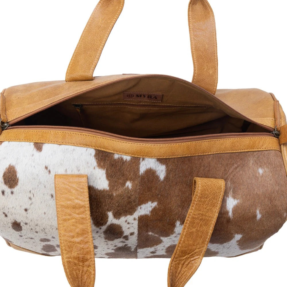 House of Hide genuine leather brown and white cowhide patterned handbag with sturdy tan leather handles on a white background