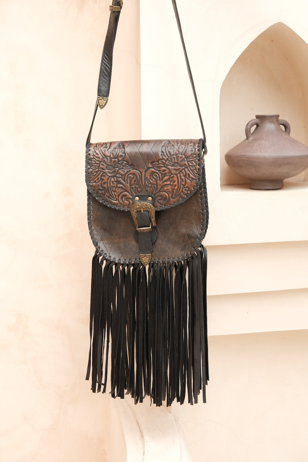 Charcoal leather crossbody bag with hand-tooled detail and tassel.