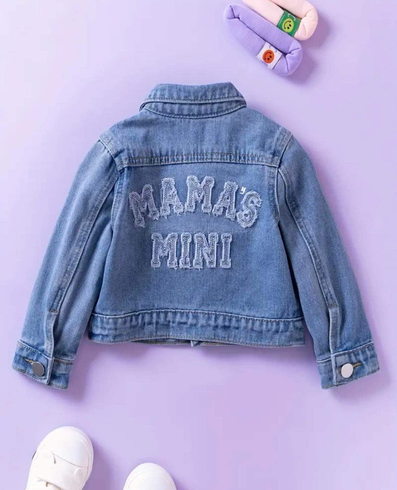 Classic denim jacket for kids laid out on a lavender backdrop, paired with colorful socks.