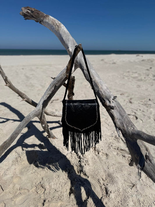 Close-up of Ebony Wild black leather handbag with detailed stone embellishments and flowing fringe tassels.