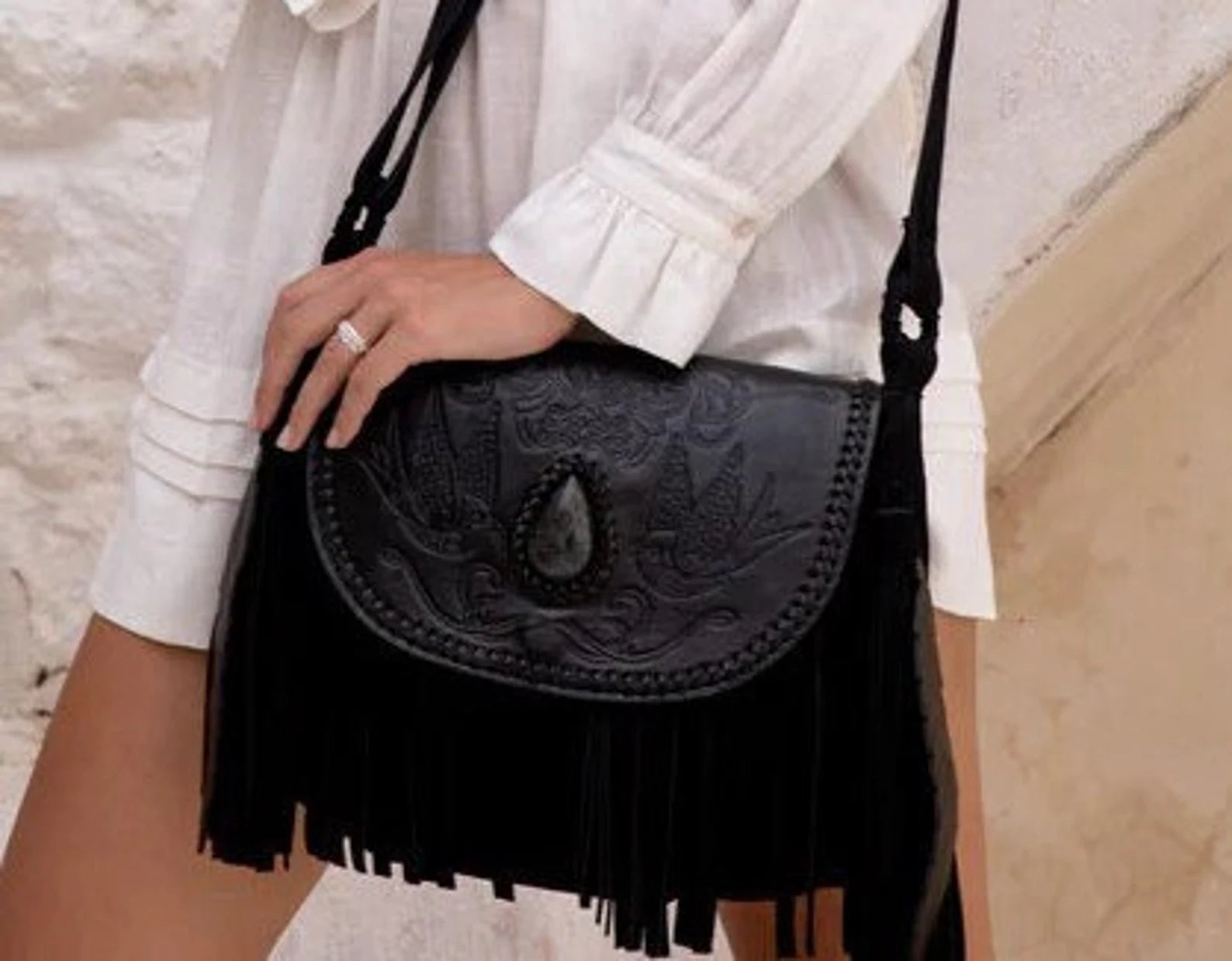 Close-up of Raven Bag’s hand-painted leather flap with labradorite gemstone and hand-tooled swallow design.