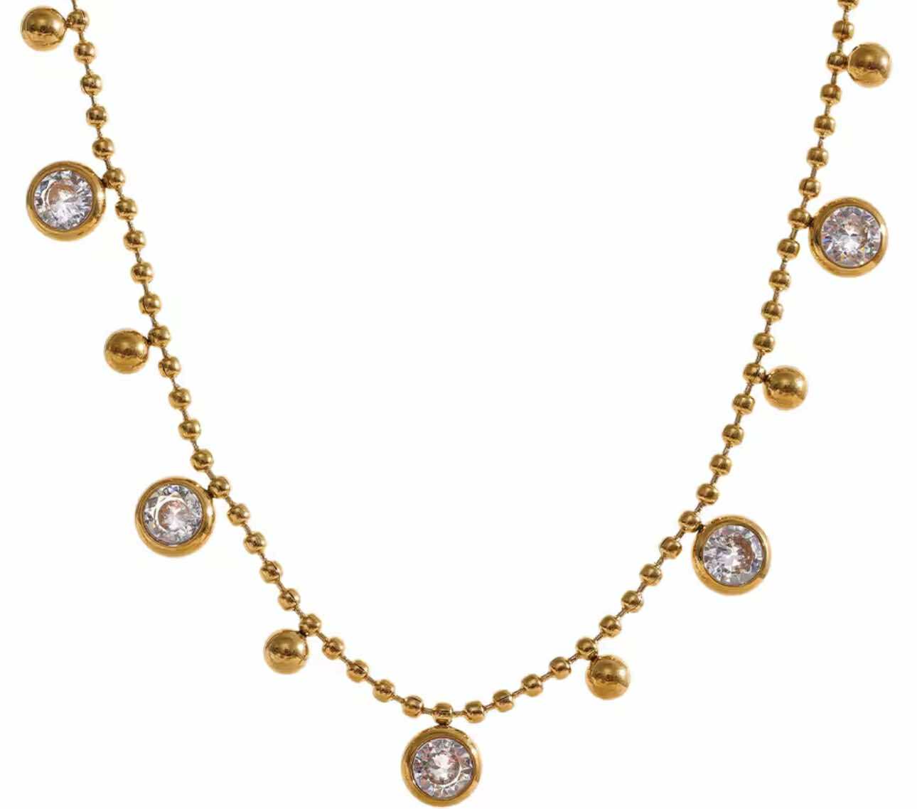 Close-up of dainty stainless steel necklace with sparkling zircon charms on gold ball chain