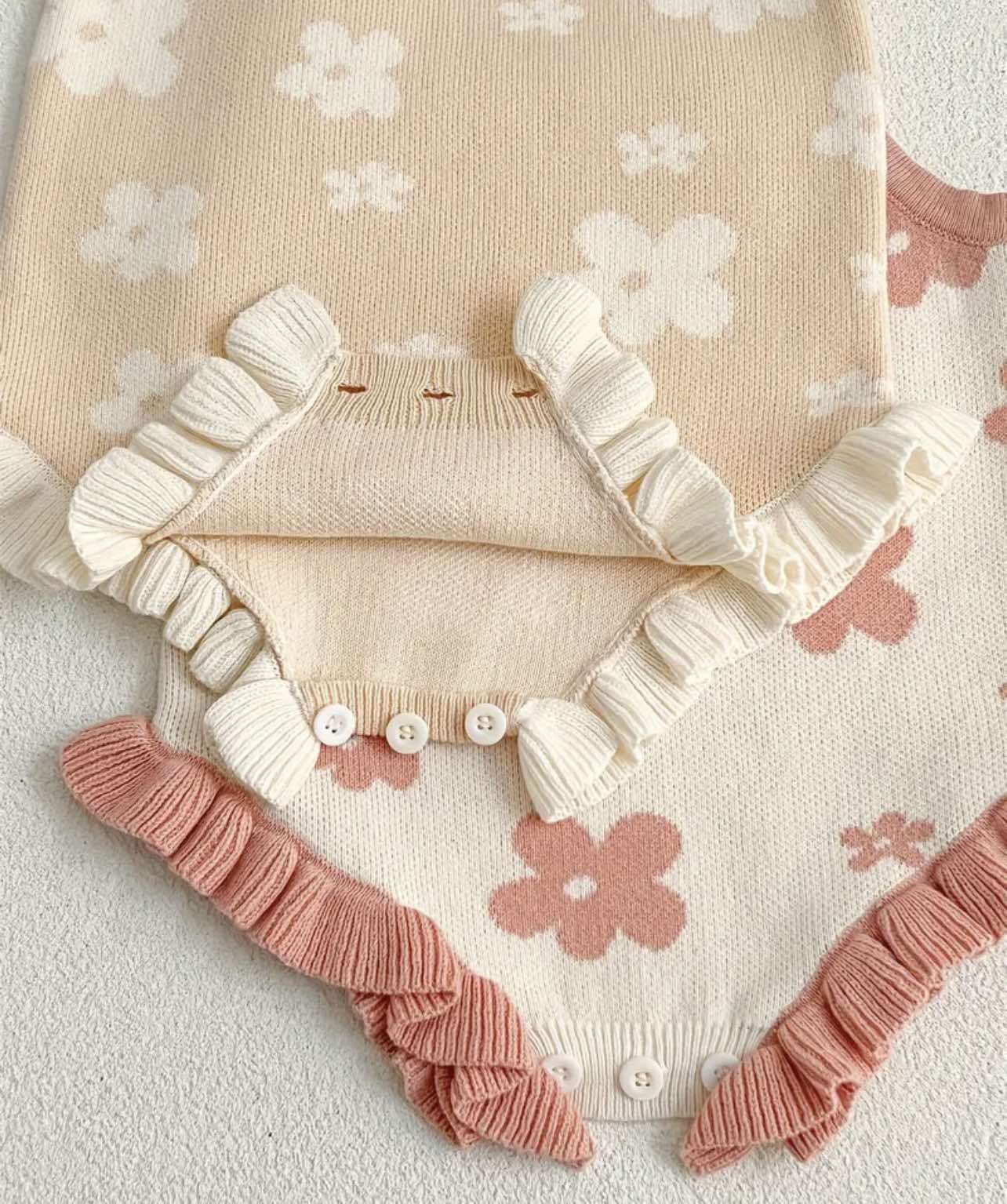 Close-up of floral pattern on baby girl romper, highlighting the intricate knit details and soft cotton material.