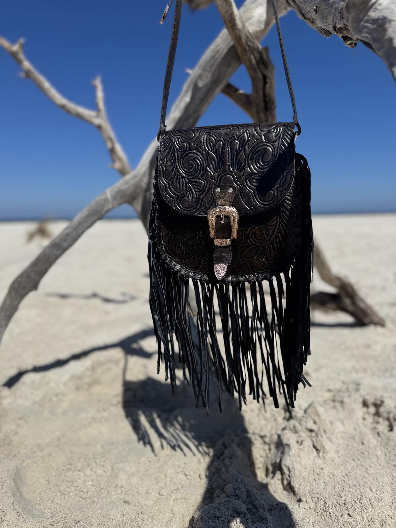 Close-up view of the Blackstone Crossbody showcasing intricate hand-tooled details and flowing leather tassels.