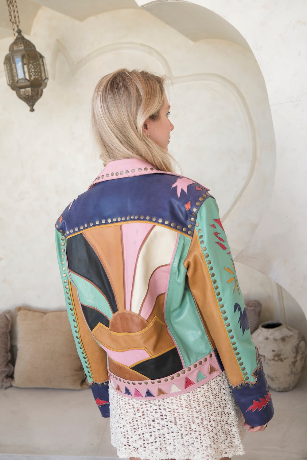 Colourful Western leather jacket for women. Handcrafted patch design with bold sunrise motif, studded trim, and festival-ready style.