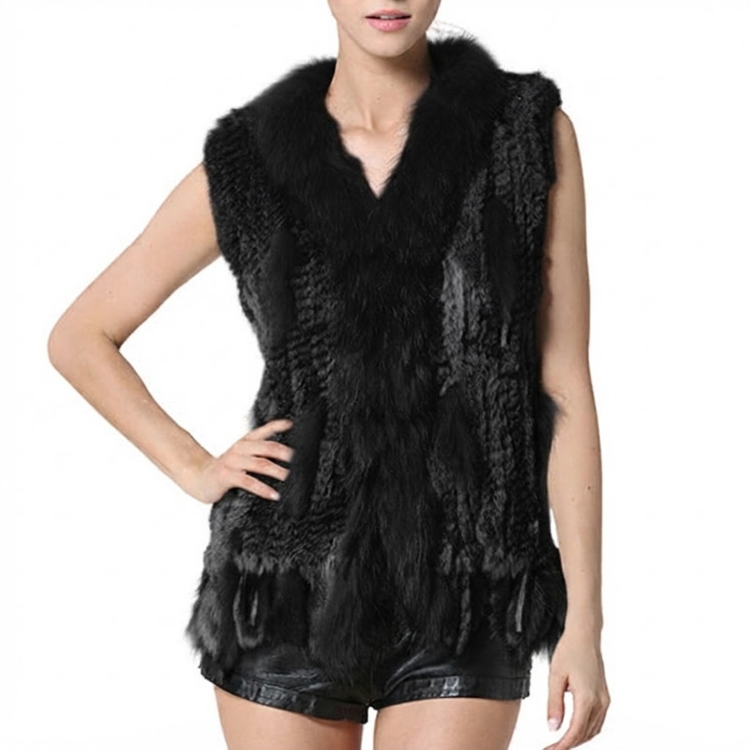 Cottontail Fur Vest from House of Hide in 100% real black rabbit fur featuring plush raccoon fur collar, fringed hem detail, minimal single button closure, lightweight sleeveless silhouette, 62-63cm length being displayed as warm versatile layering vest without bulk on styled backdrop