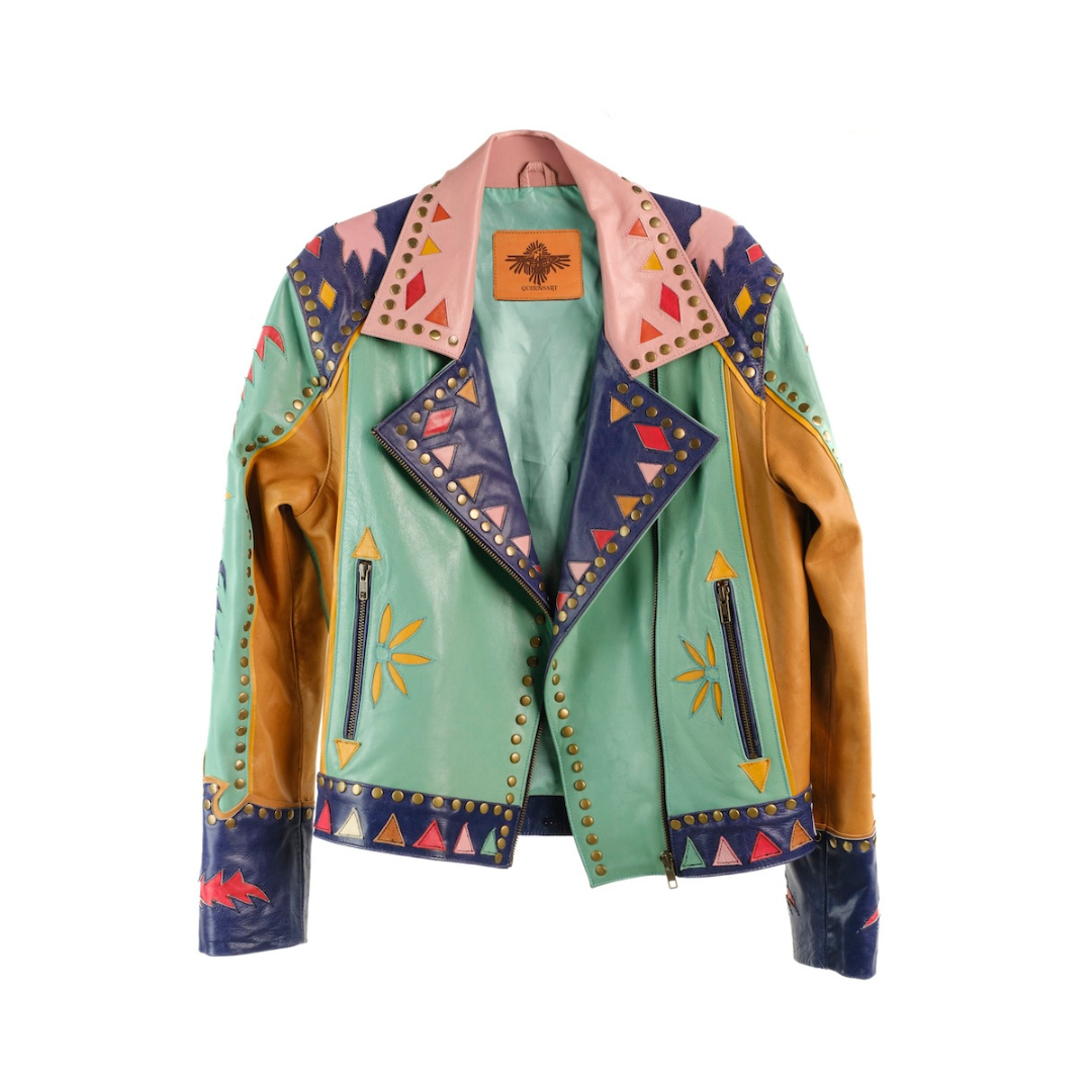 A multicolor patchwork leather jacket with mint green panels, tan suede sleeves, navy blue geometric-triangle-trimmed lapels, and a pink collar, shown on a white background
