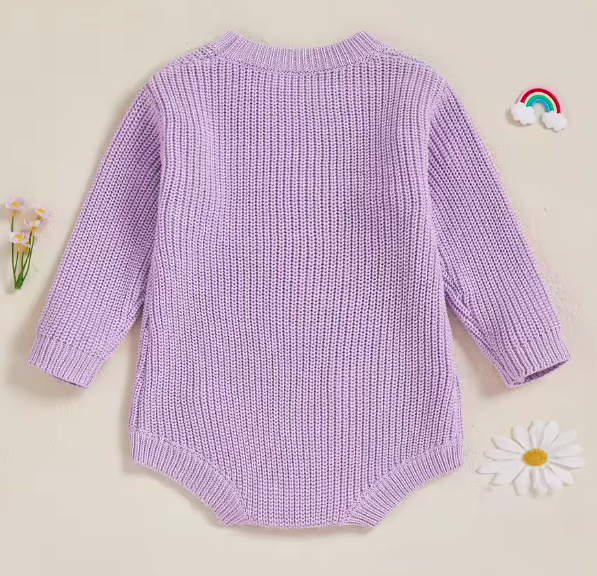 Flat lay of baby arrival gift romper with “Little Sister” embroidery