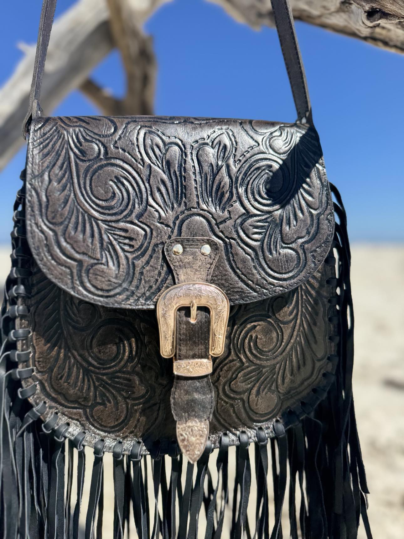 Front view of the Blackstone Crossbody bag with hand-tooled leather design and elegant black tassels.